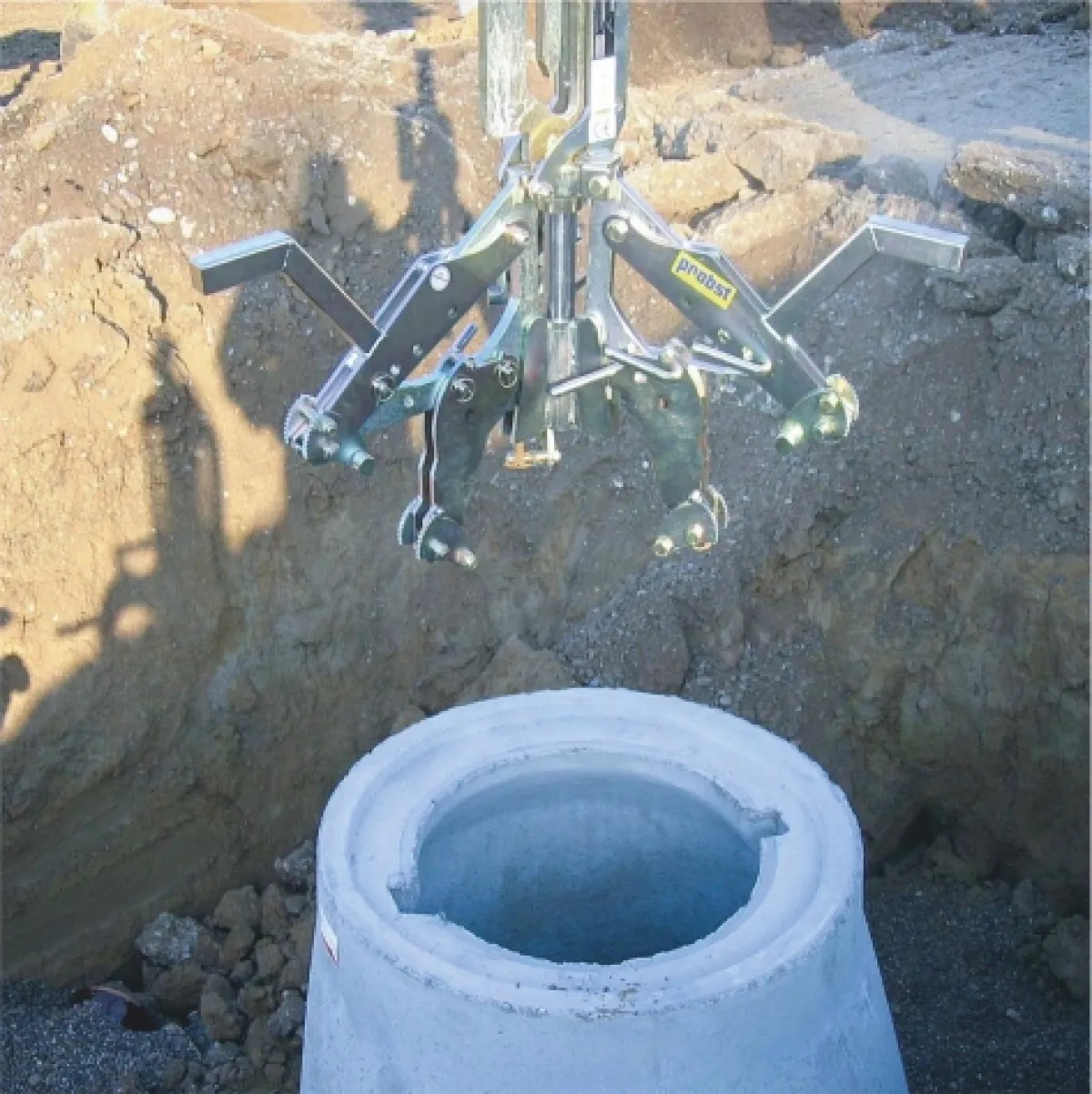 FE 1067 aknaemelő automatikus kioldása lehelyezés után | Texem A beton aknaelem talajra helyezése után önműködően szétkapcsolt és szabadon lógó FE 1067 mechanikus emelőolló | Texem